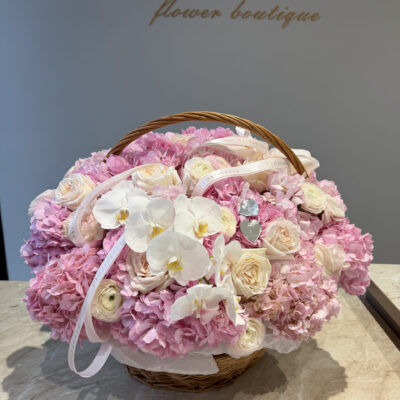 Рожева композиція в корзині з ранункулюсами, піоновидими трояндам та ніжними орхідеями