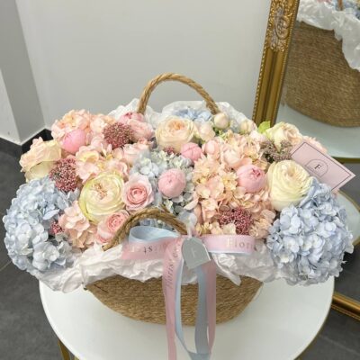 Композиція в плетеній сумці з гортензій, троянд та озотамнусу