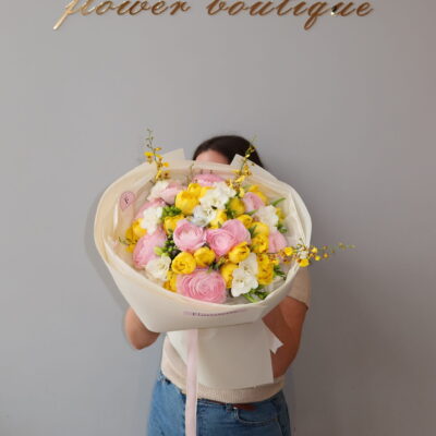 Яскравий букет з ранункулюсів, фрезій, ароматного онцидіуму та жовтих тюльпанів