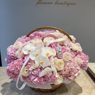 Рожева композиція в корзині з ранункулюсами, піоновидими трояндам та ніжними орхідеями